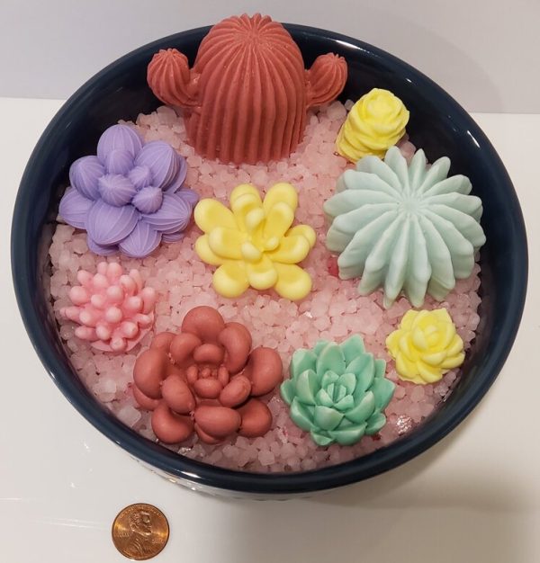 colorful soaps in the shape of cacti and succulents in a blue bowl with bath salts