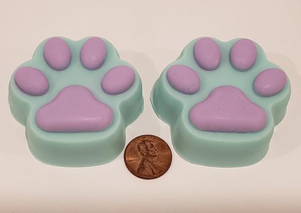 two soaps that look like paws with a penny to show scale