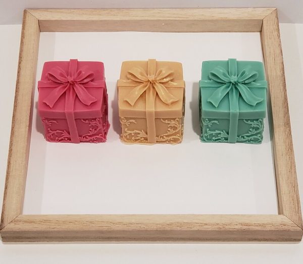 red gold and green goat milk soap in the shape of a one inch cube wrapped present with a bow