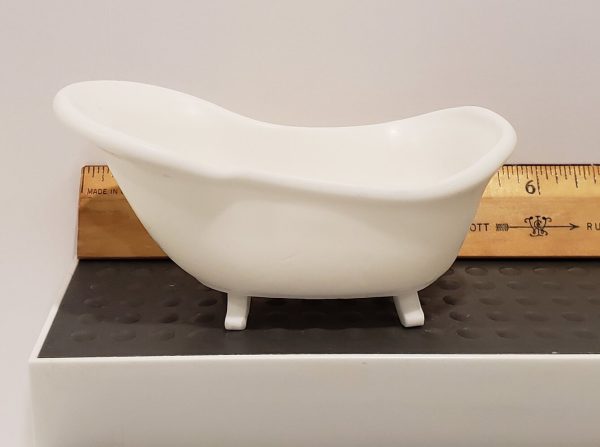 small white soap shaped like a bathtub on a shelf with a ruler behind it to show size and scale