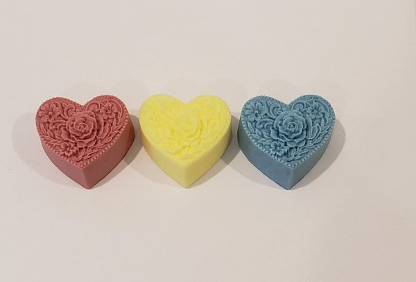 three heart shaped soaps with a rose shape on each soap