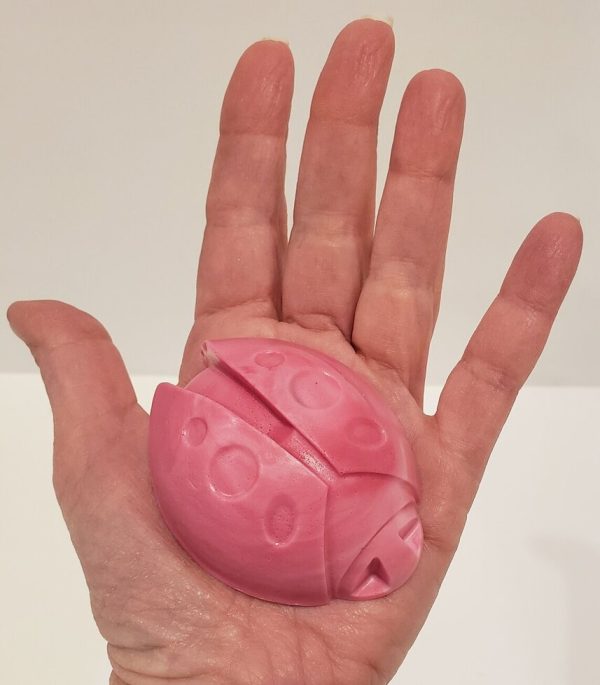 pink soap held in a hand, shaped like a ladybug