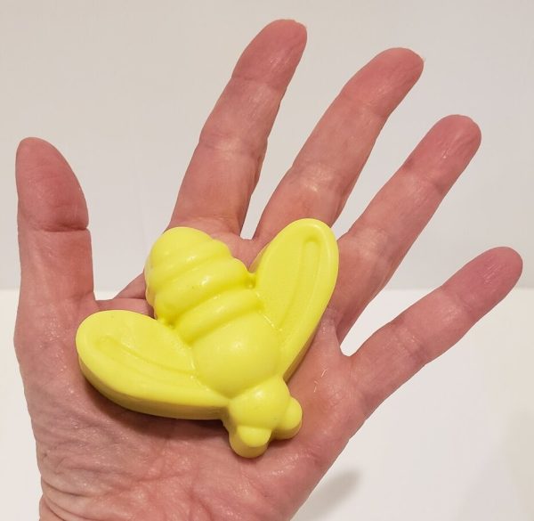 yellow soap held in a hand, shaped like a bee